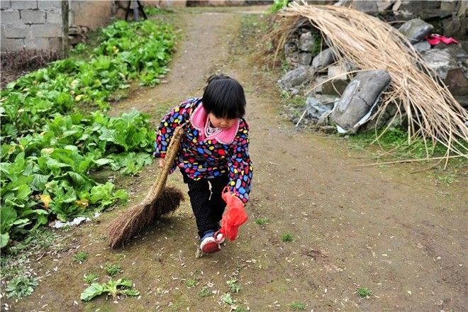 Miaomiao sweeps the road to her home, in an isolated village in Yichang city, Central China's Hubei province, Feb 23. Parentless, the first-grader has taken up a lot of resposibility in the family. Her grandmother, who is approaching her 60s, is mentally disabled, handicapped in the right arm, and is frail. Her grandfather suffered severe cracked skin disease, which makes him unable to be exposed to water especially in the winter. 